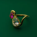 Amara Gold ring with a red gemstone and clear teardrop gemstone on a green background