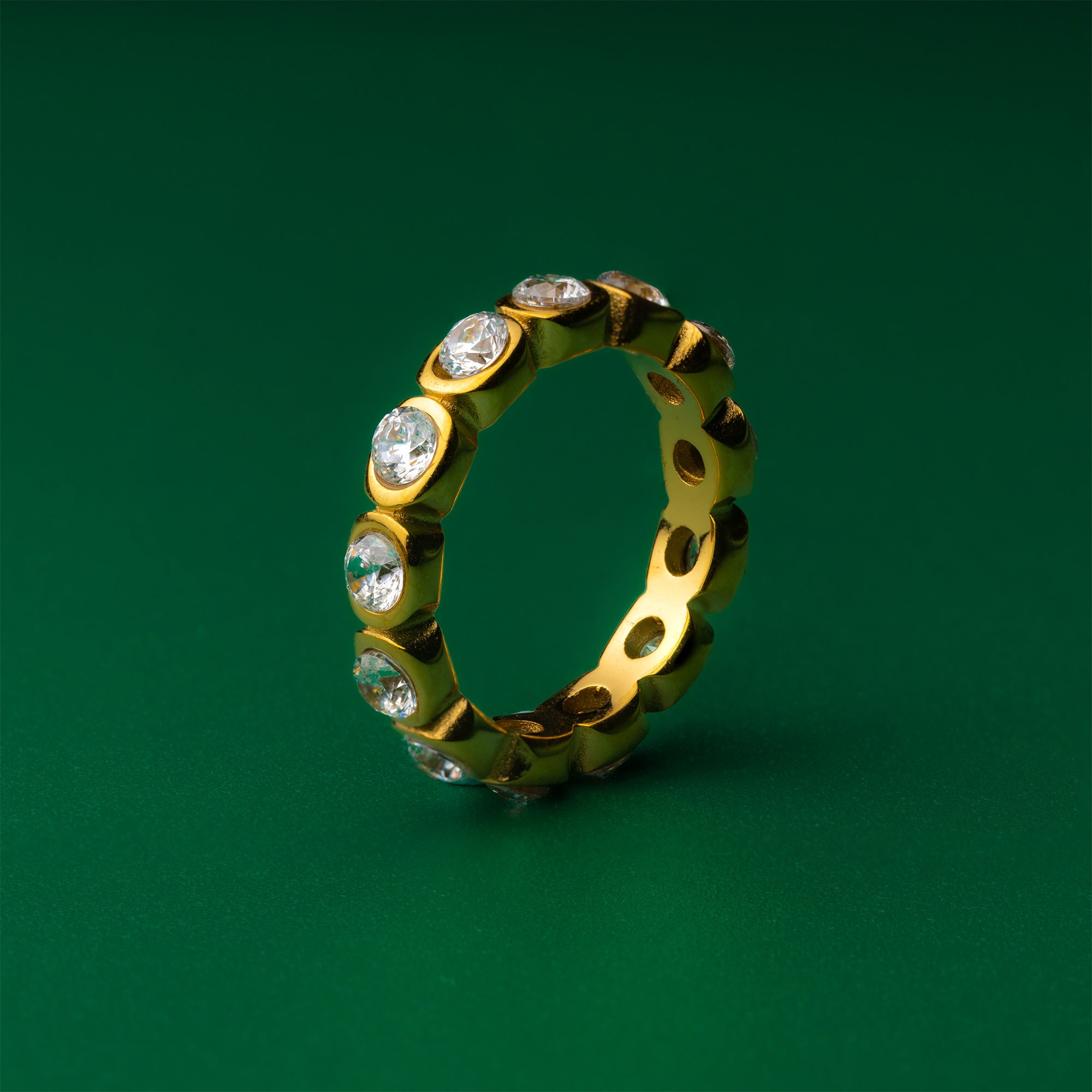 Amber Oval Bezel Gold ring with embedded diamonds on a green background