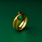 Ariana diamond gold ring with a green gemstone on a green background