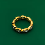 Bezel set gold ring with embedded stones on a green background