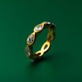 Bezel set gold ring with embedded stones on a green background