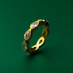 Bezel set gold ring with embedded stones on a green background