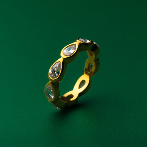 Bezel set gold ring with embedded stones on a green background
