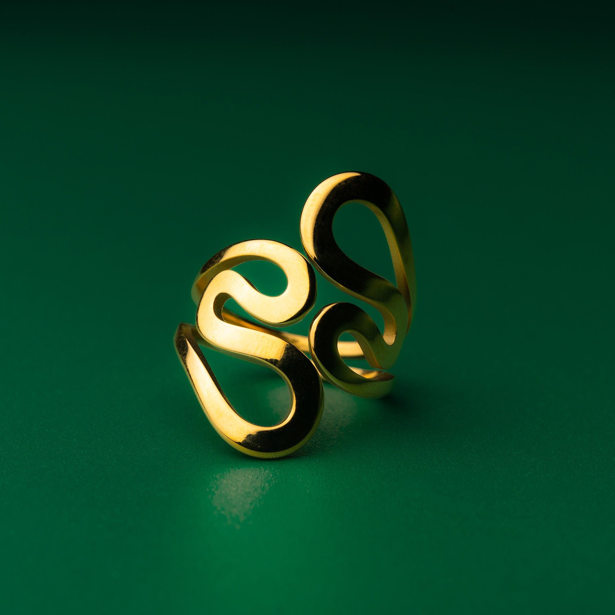 Coastal wave gold ring with a unique design on a green background