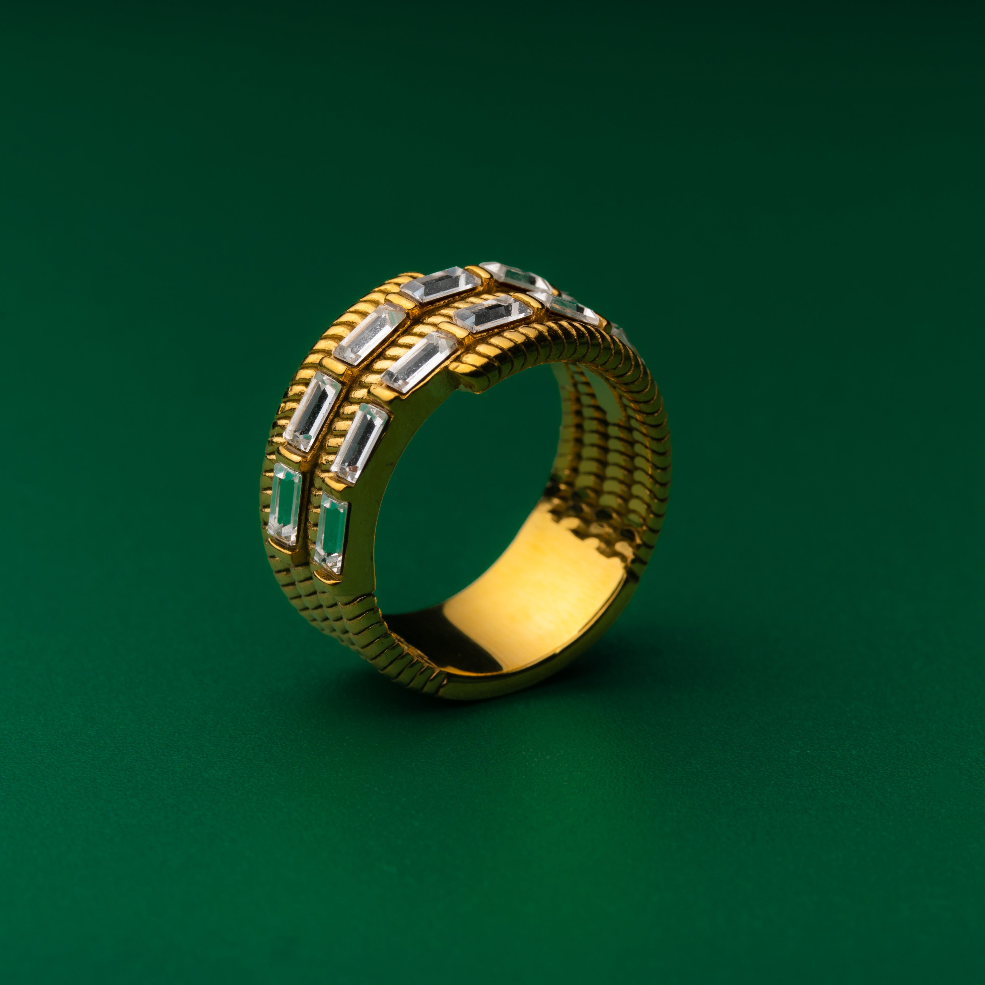 Elevation gold ring with gemstones on a green background