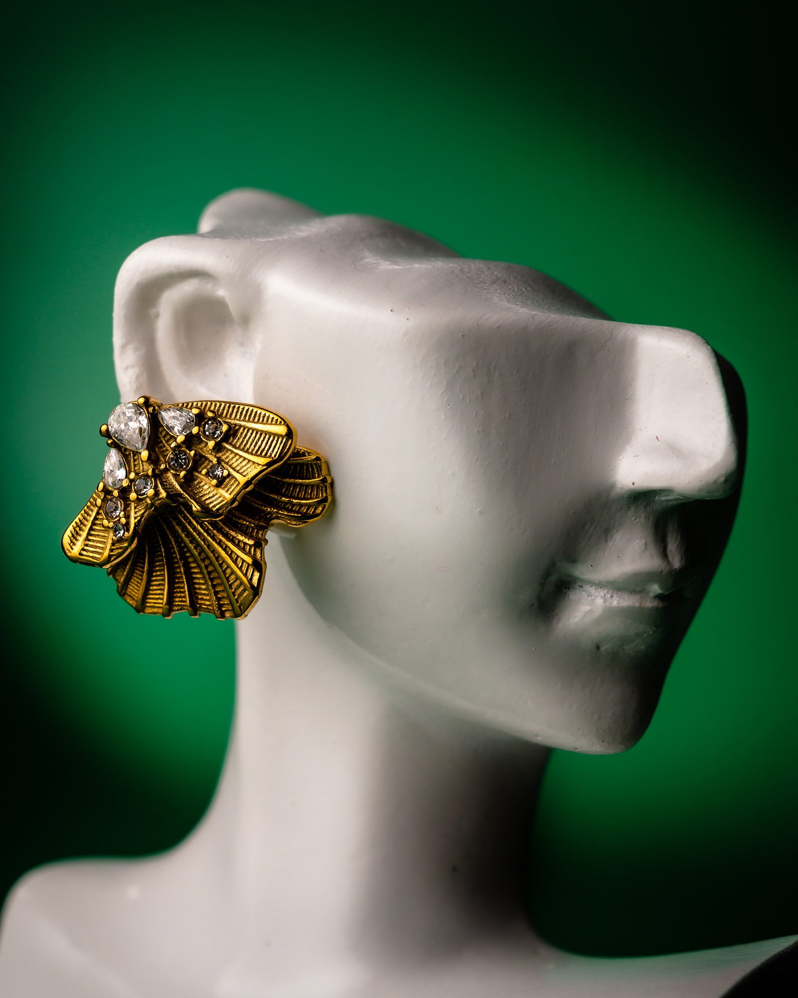 Gold golden shell studs earring on a mannequin ear with a green background
