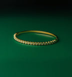Ice queen gold bangle with embedded diamonds on a green background