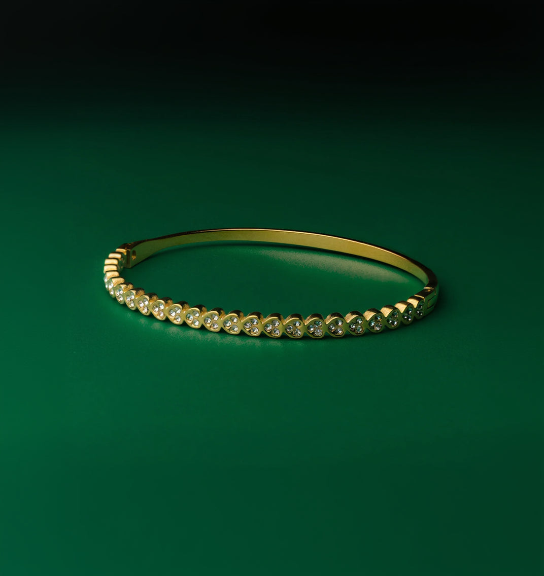 Ice queen gold bangle with embedded diamonds on a green background