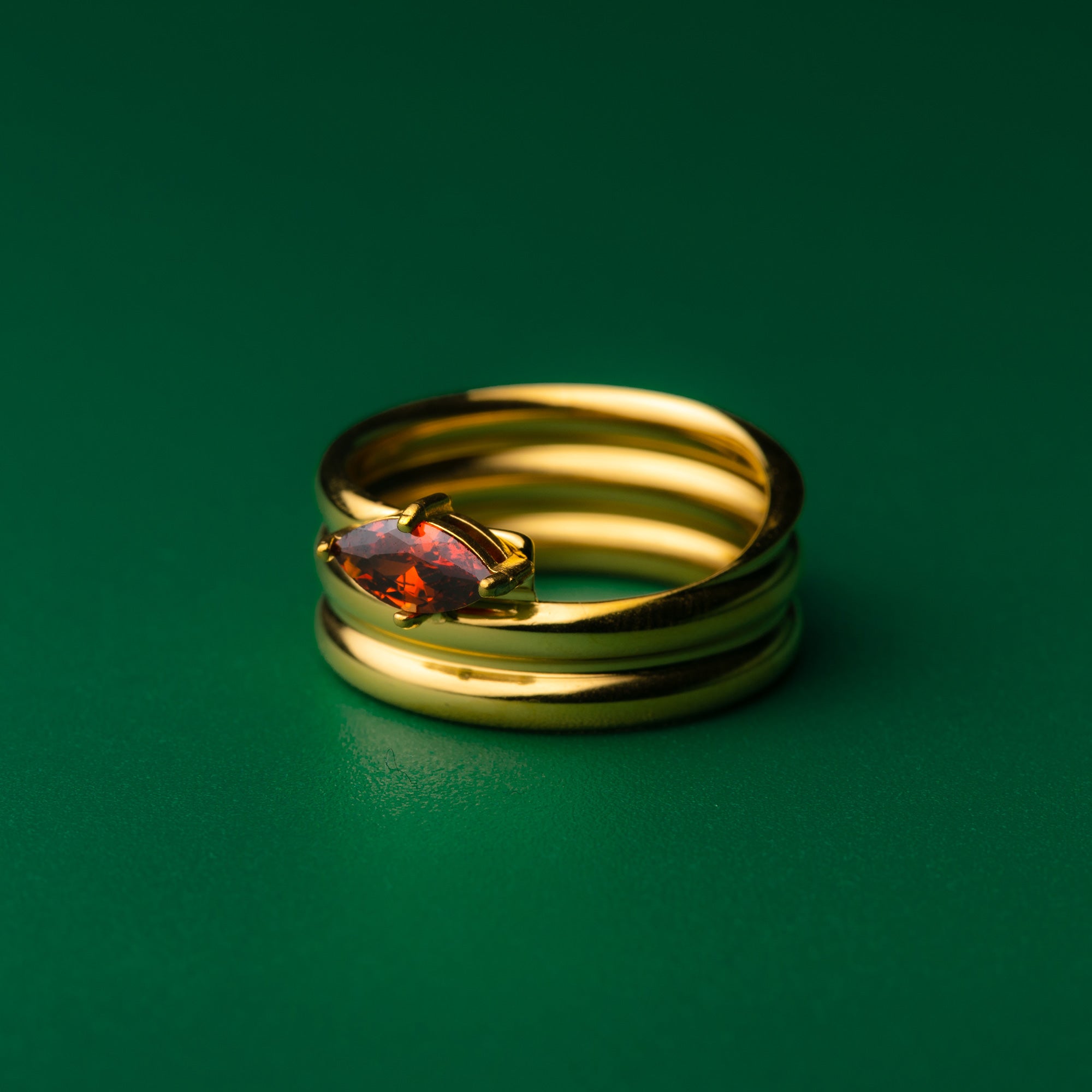 Isabella solitaire stack gold ring with a gemstone on a green background