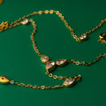 Lotus grace gold necklace with teardrop-shaped gemstones on a green background