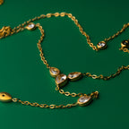 Lotus grace gold necklace with teardrop-shaped gemstones on a green background