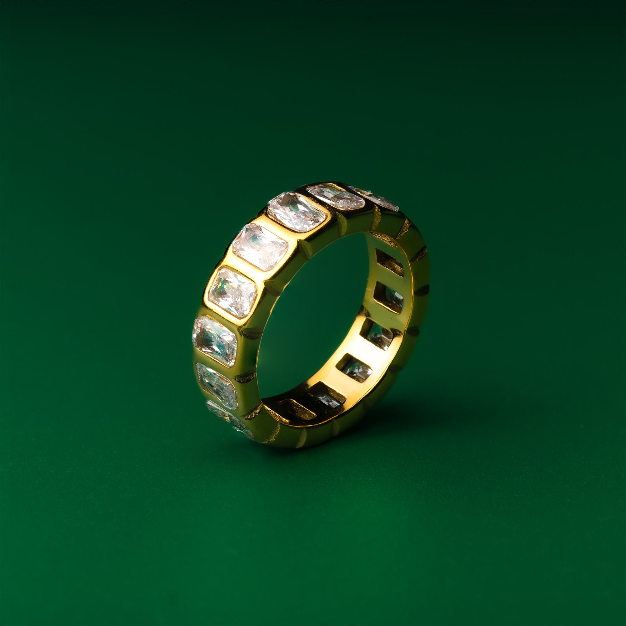 Luna eternity gold ring with embedded gemstones on a green background