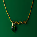Midnight muse green gold necklace with a green gemstone pendant on a green background