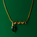 Midnight muse green gold necklace with a green gemstone pendant on a green background
