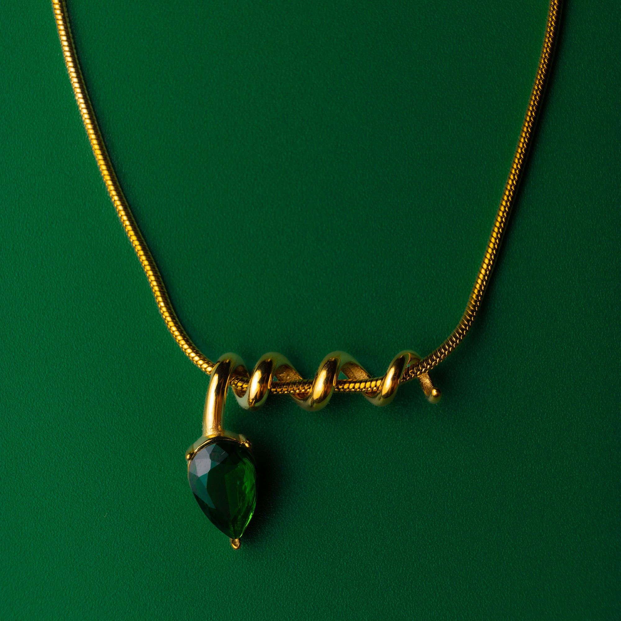 Midnight muse green gold necklace with a green gemstone pendant on a green background