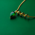Midnight muse green gold necklace with a green teardrop pendant on a green background