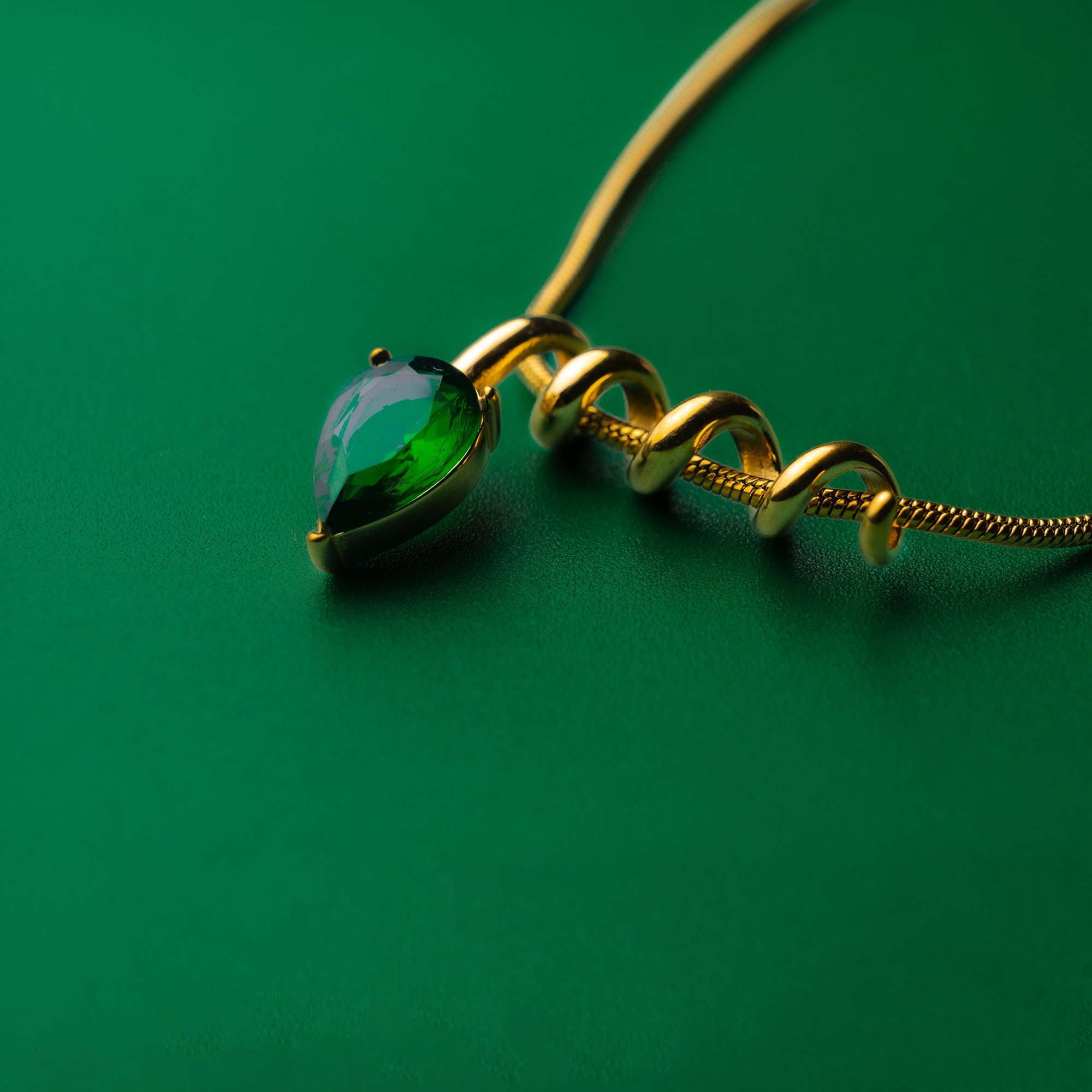 Midnight muse green gold necklace with a green teardrop pendant on a green background