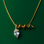 Midnight muse gold necklace with a teardrop-shaped gem pendant on a green background