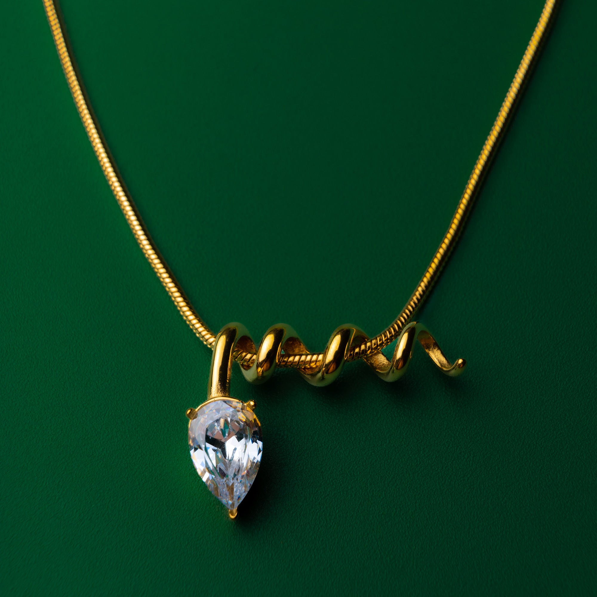 Midnight muse gold necklace with a teardrop-shaped gem pendant on a green background