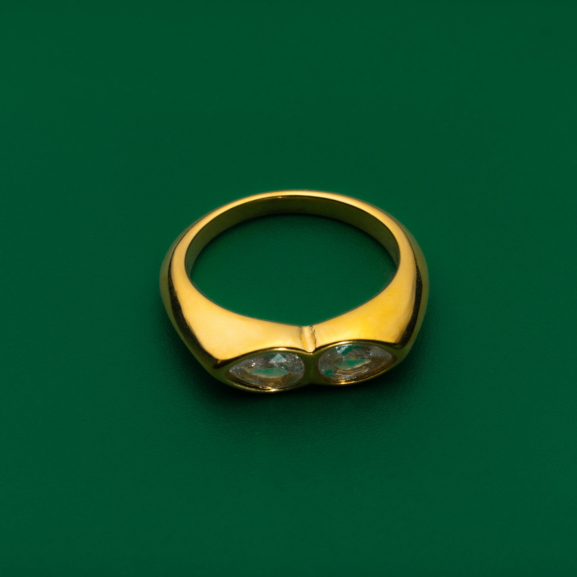 Mystic eyes gold ring with two stones on a green background