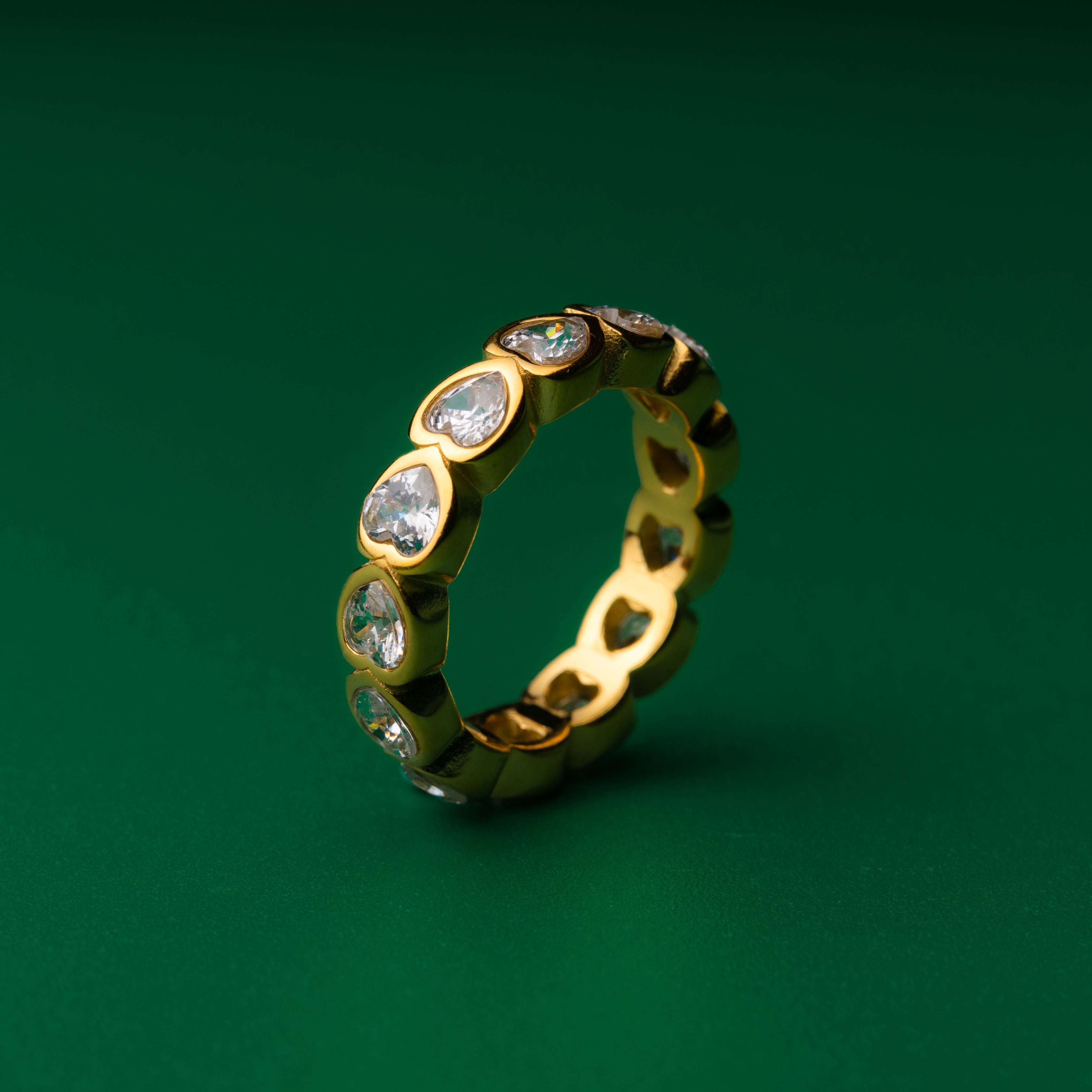 Romantic heart Gold ring with embedded diamonds on a green background