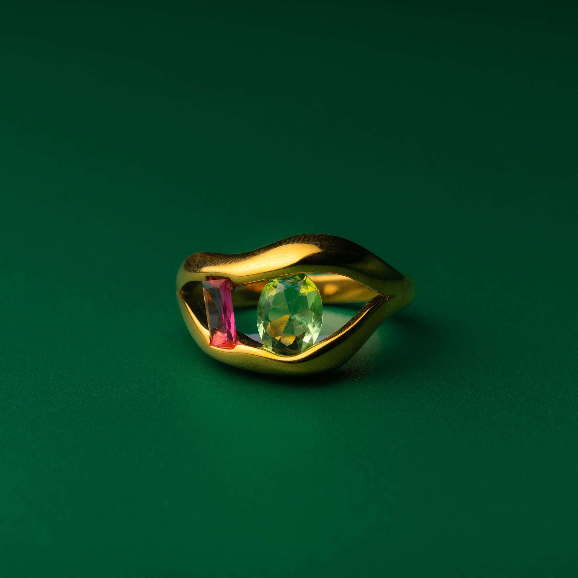 Sierra's gemstone gold ring with gemstones on a green background