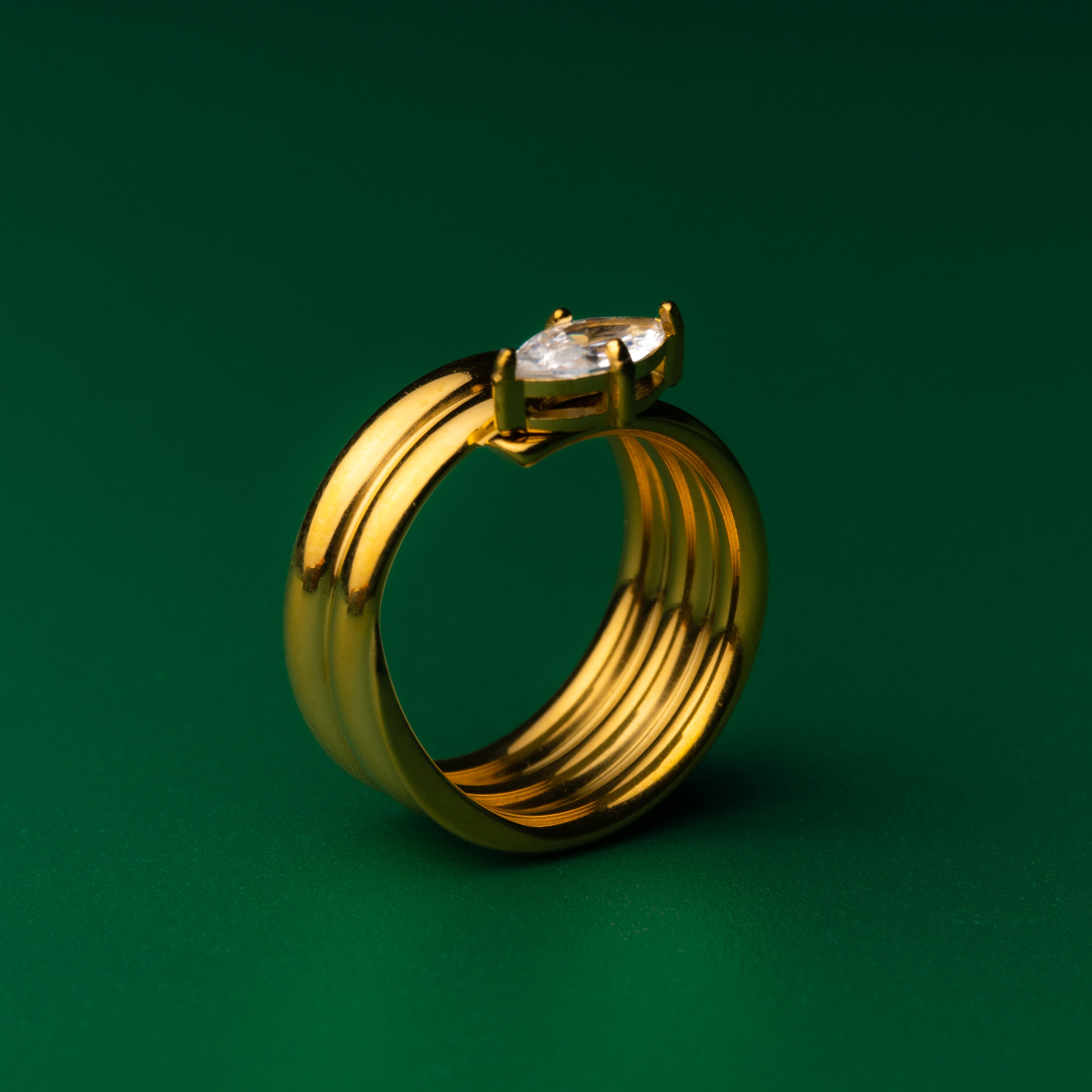 Solitaire stack gold ring with a gem on a green background
