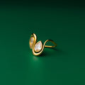 Teardrop goldring with two pear-shaped gemstones on a green background